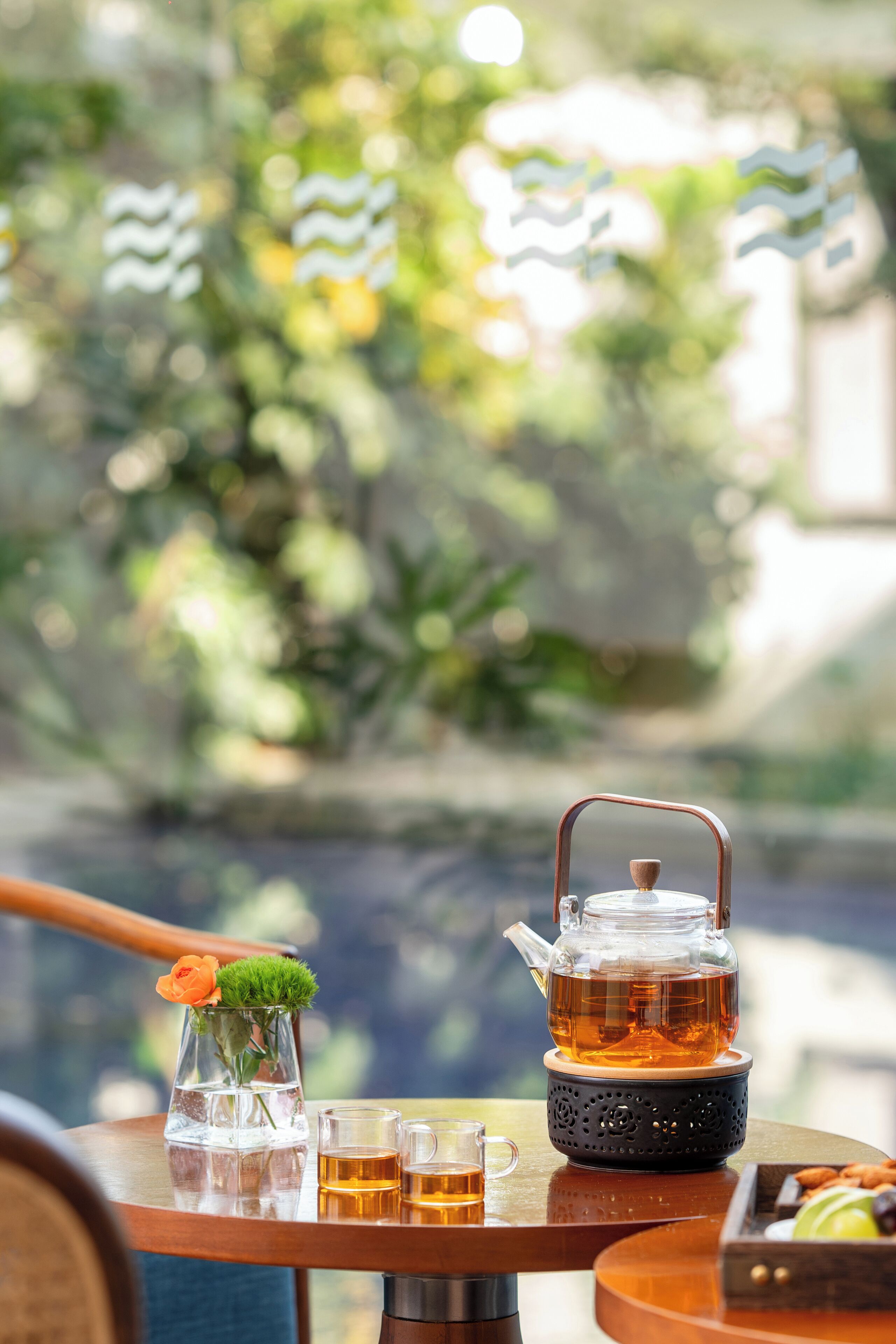 A table with a teapot, glasses, and a small vase with a flower.