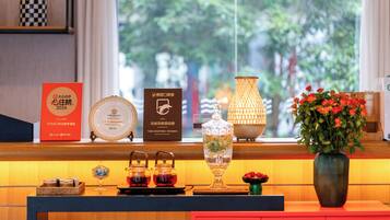 A hotel reception desk with a window view, a vase of flowers, and various decorative items.