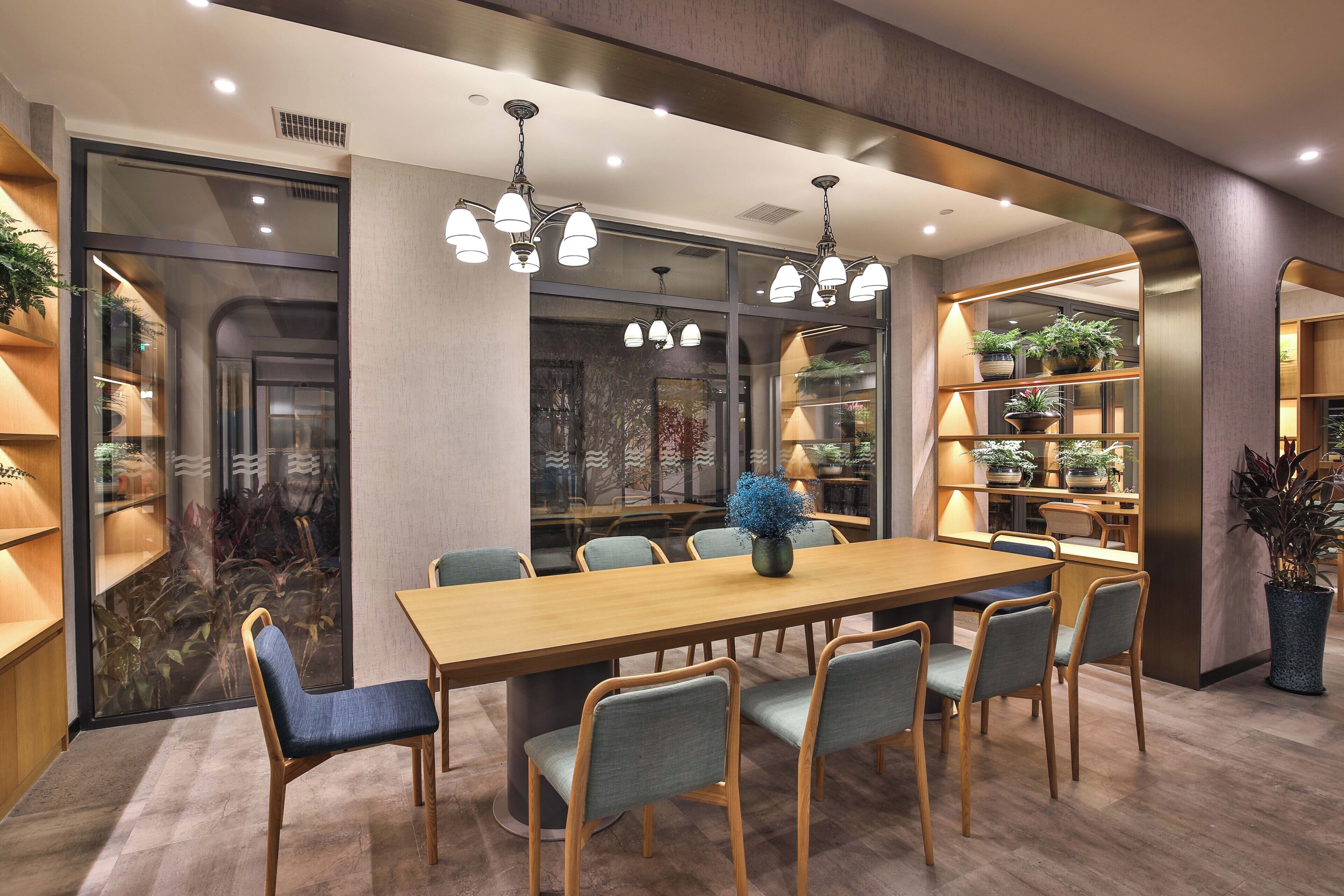 A modern dining area with a wooden table, six chairs, and pendant lighting.