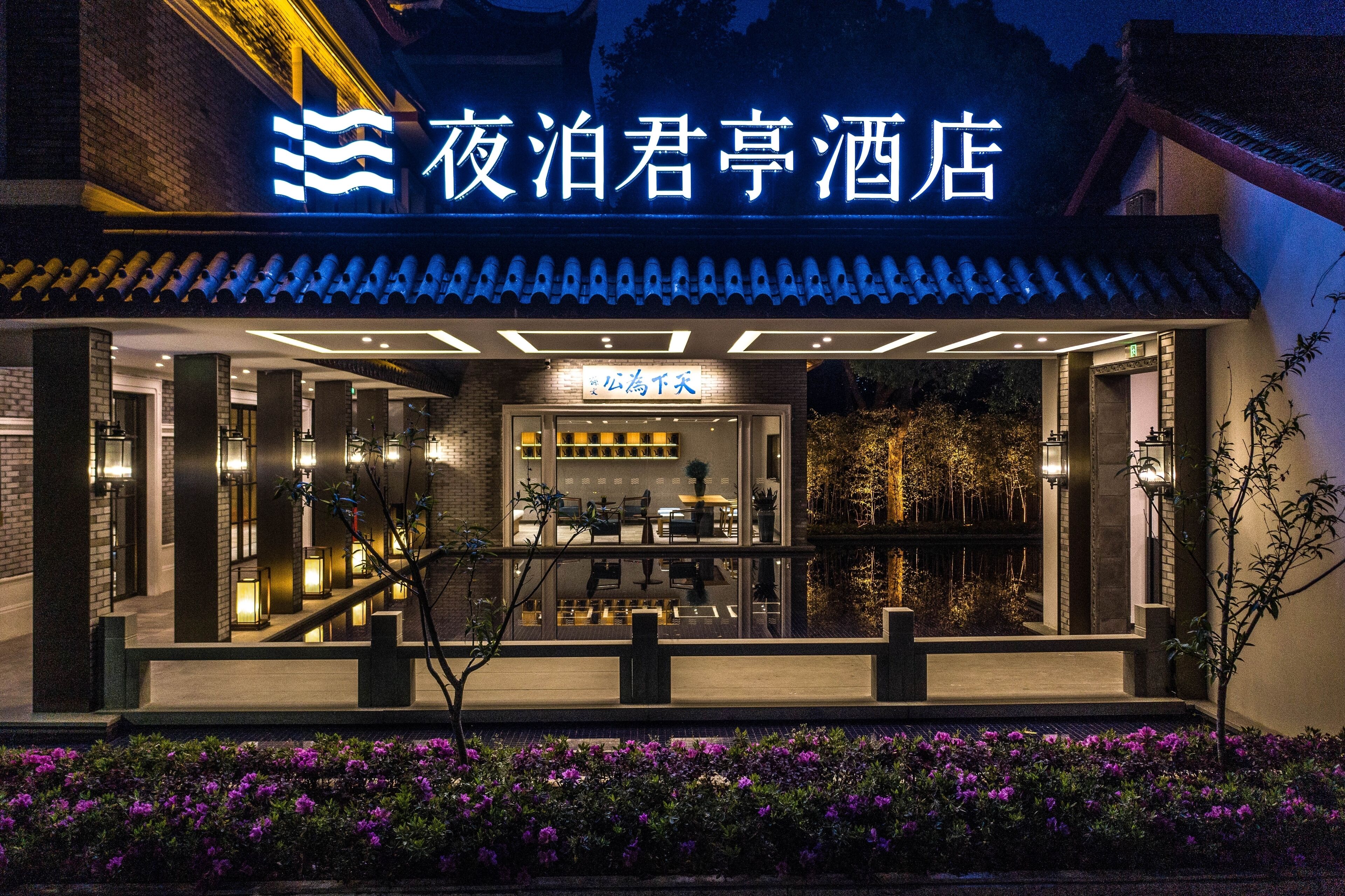 Een hotel in traditionele Chinese bouwstijl, met een betegeld dak en een goed verlichte ingang.