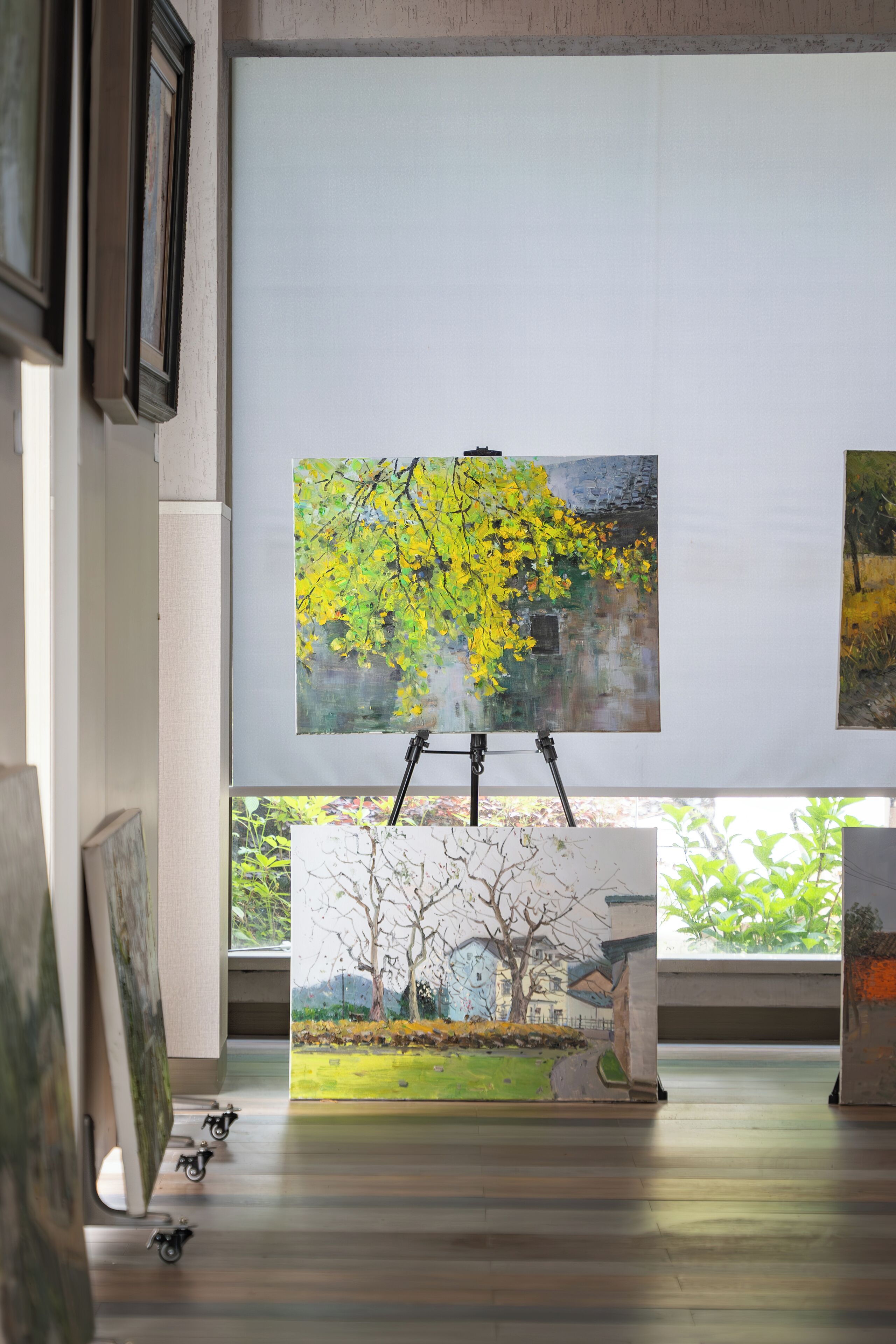 An art gallery with paintings on easels and a wooden floor.
