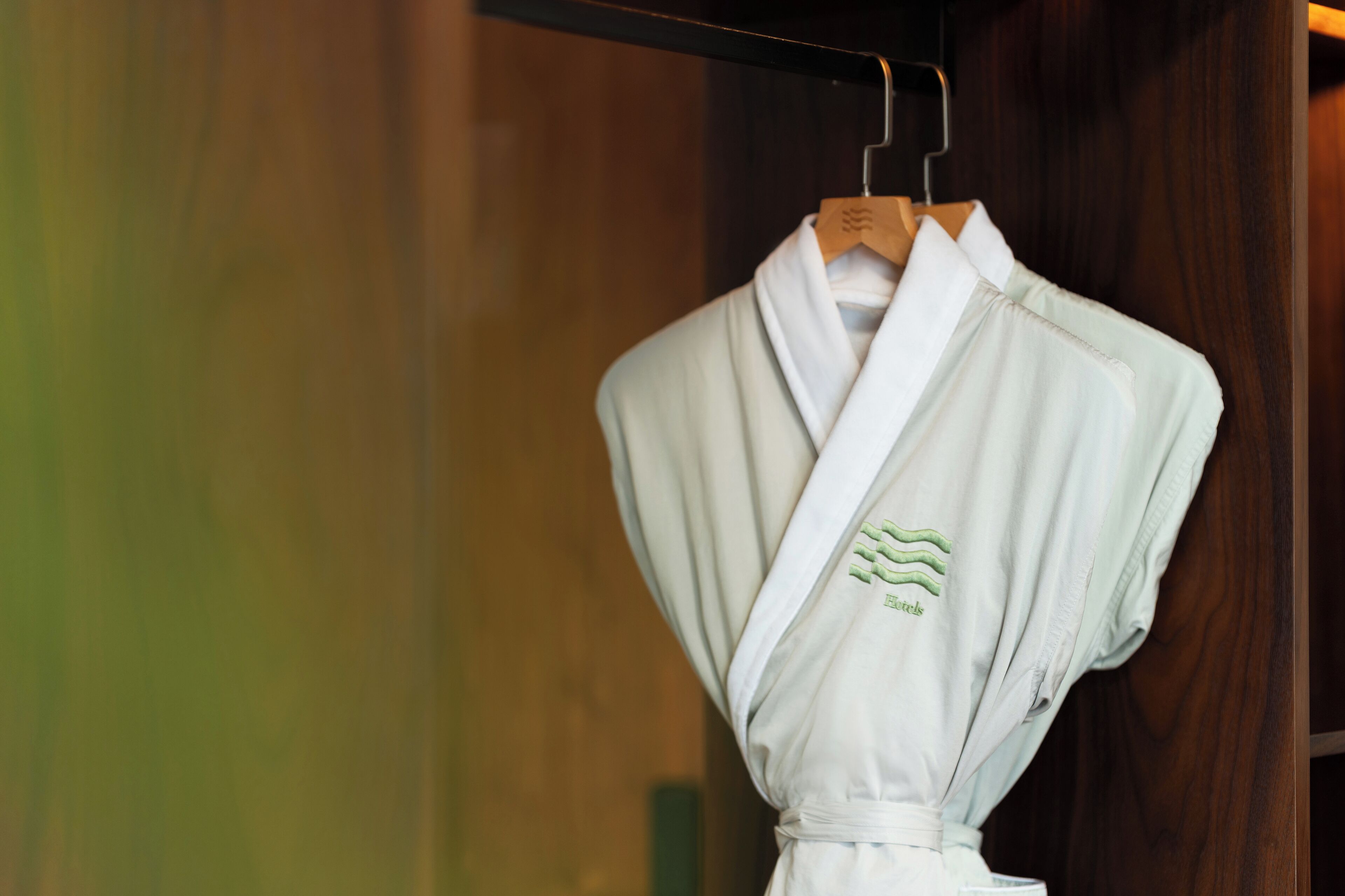 A white robe hanging on a wooden hanger in a wooden closet.