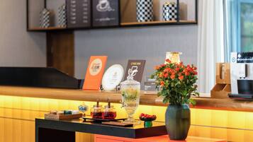 Una mesa de recepción con un florero, una cafetera y un panel de menú.