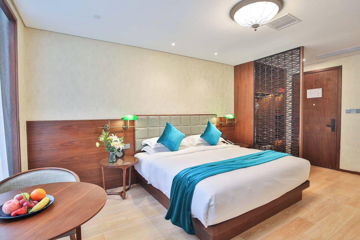 Une chambre d’hôtel avec un lit, des tables de chevet, un panier de fruits et un plancher en bois.