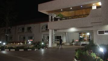 A hotel with a modern design, featuring a two-story structure, a covered outdoor area, and a well-lit entrance.