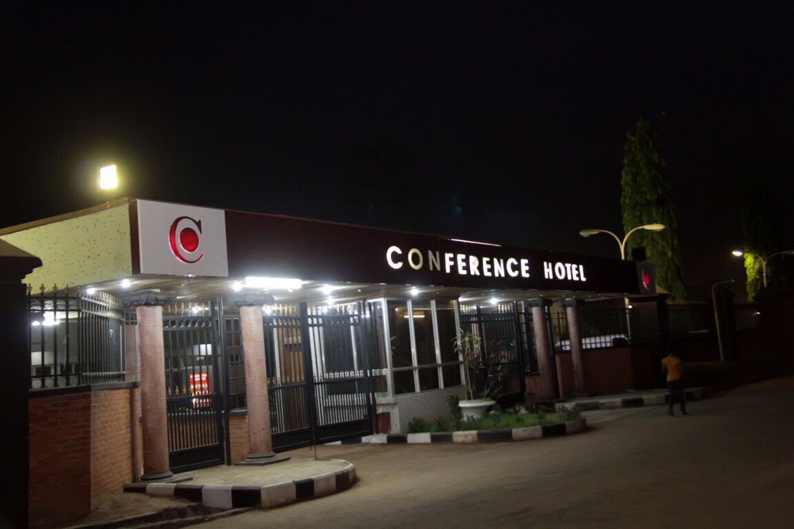 A conference hotel with a prominent sign, a gated entrance, and a well-lit facade.