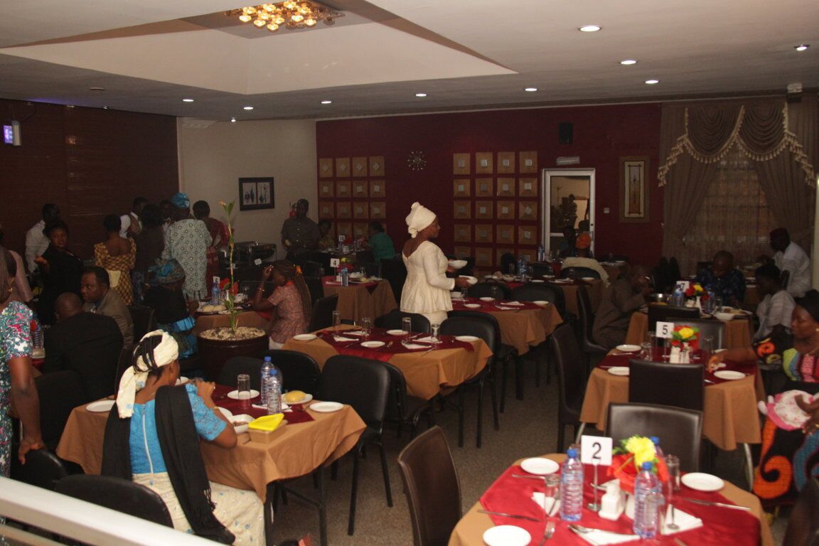 A dining area with multiple tables, some with water bottles and plates, and a few people seated.