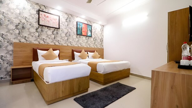 Una habitación de hotel moderna con dos camas de madera, una pared con diseño de mármol y un ventilador de techo.