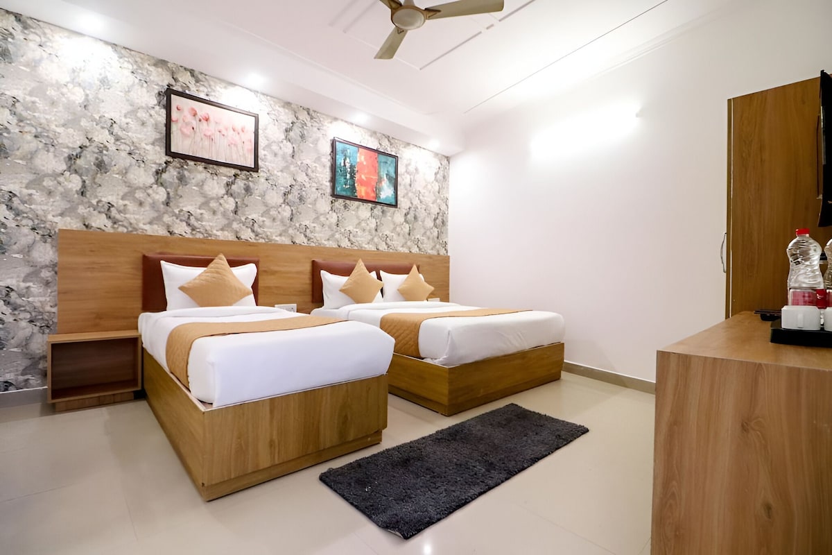 A modern hotel room with two wooden beds, a marble-patterned wall, and a ceiling fan.