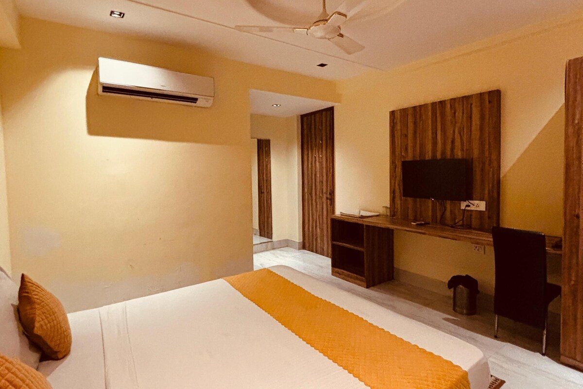 A hotel room with a bed, a desk, a television, and a ceiling fan.