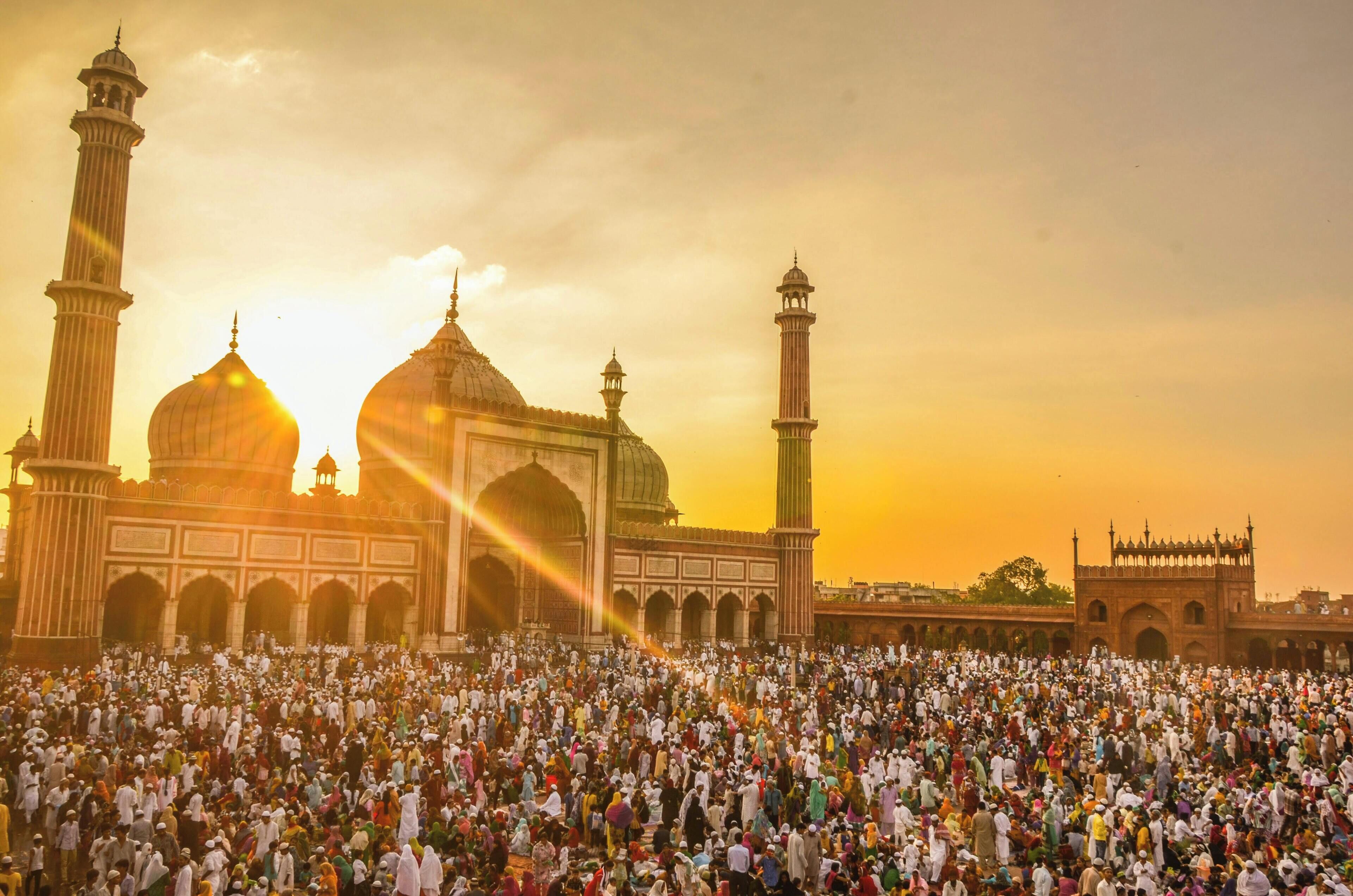 A large mosque with multiple domes and minarets, surrounded by a crowd of people.