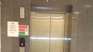 Un ascensor con panel de control, señal que indica socios de entrega de alimentos e instrucciones de emergencia.
