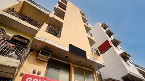 Un edificio de varios pisos con balcones, unidades de aire acondicionado y un cartel que dice 'GOLD STAY'.