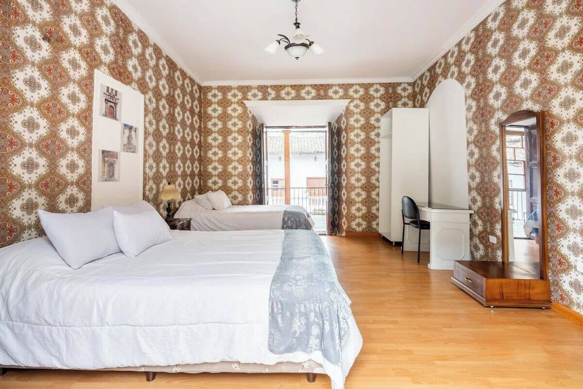 A bedroom with a large bed, a desk, and a mirror.