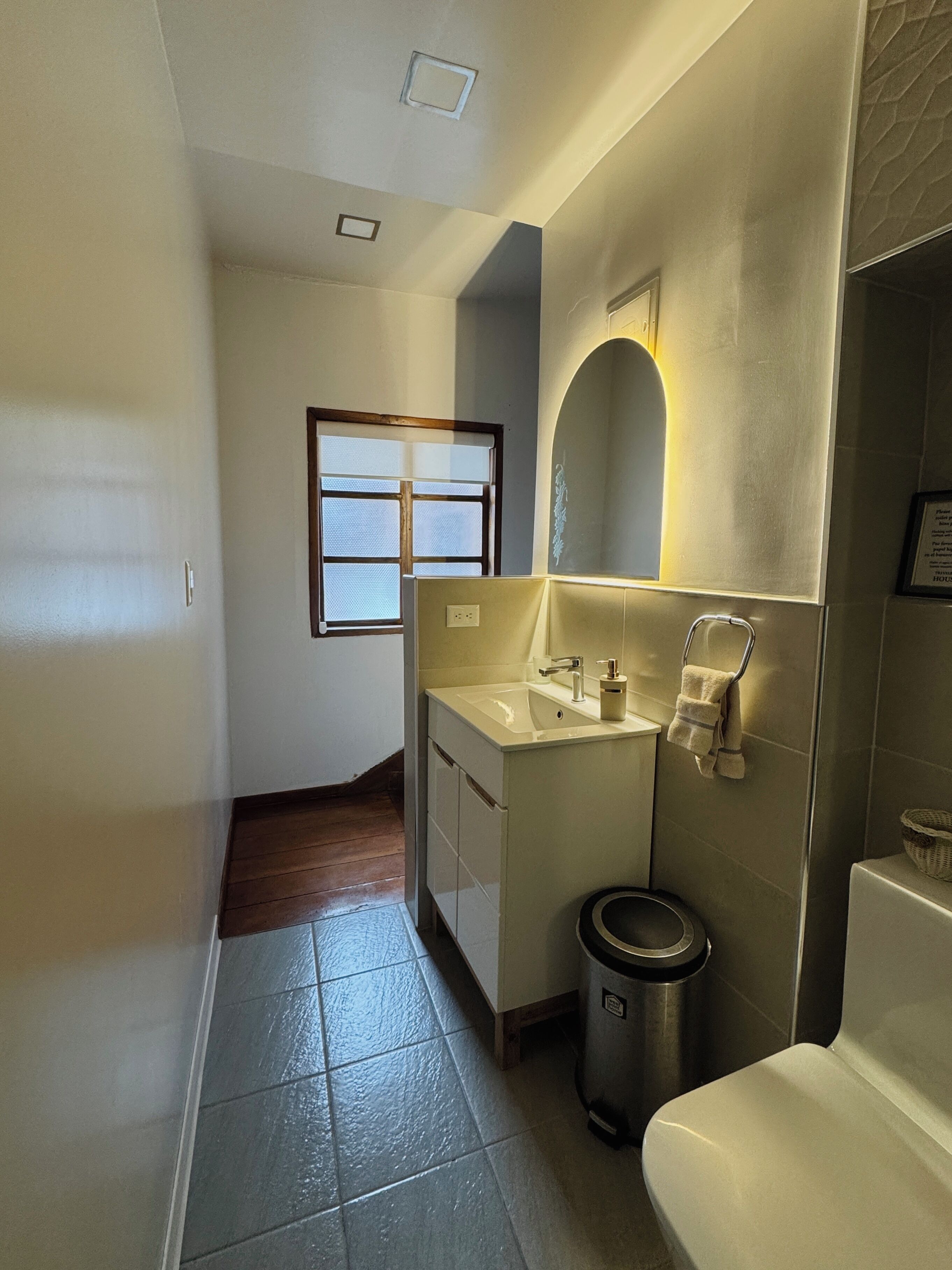 Ein kleines Badezimmer mit Waschbecken, Spiegel und Toilette.