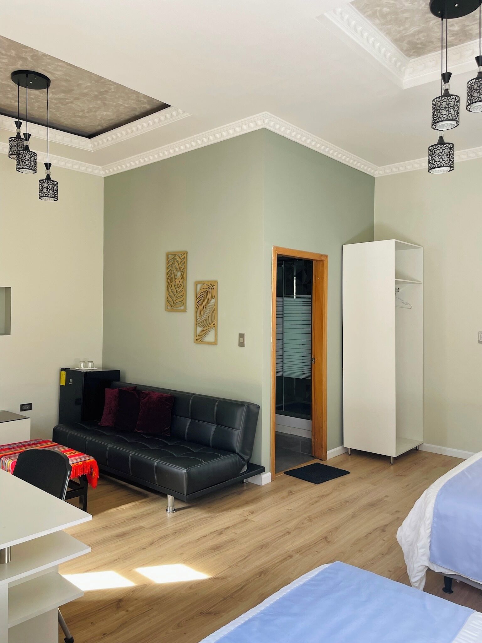 Una habitación moderna con un sofá de cuero negro, un armario blanco y una mesa de comedor.