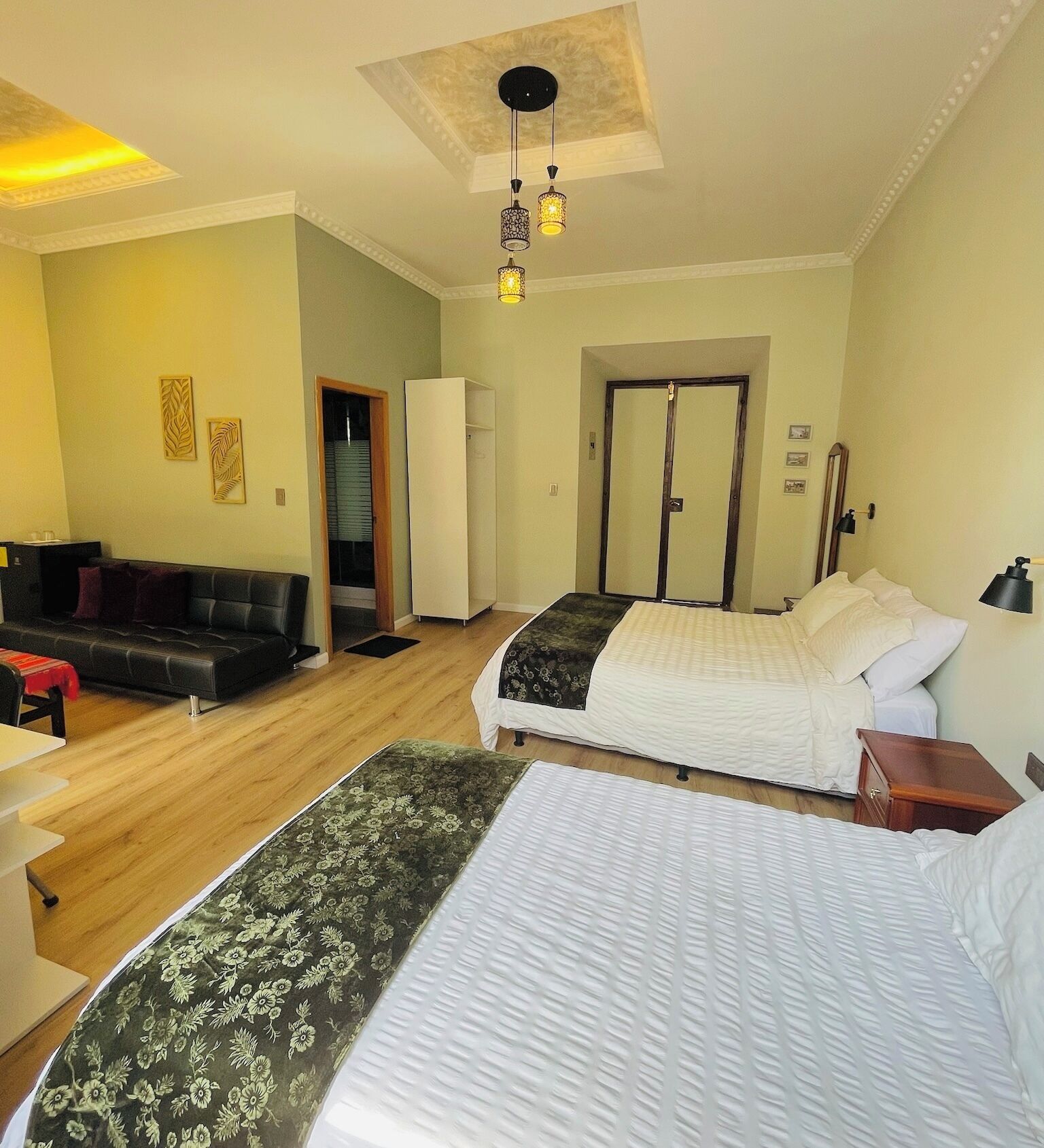 A hotel room with two beds, a sofa, a desk, and a wardrobe.