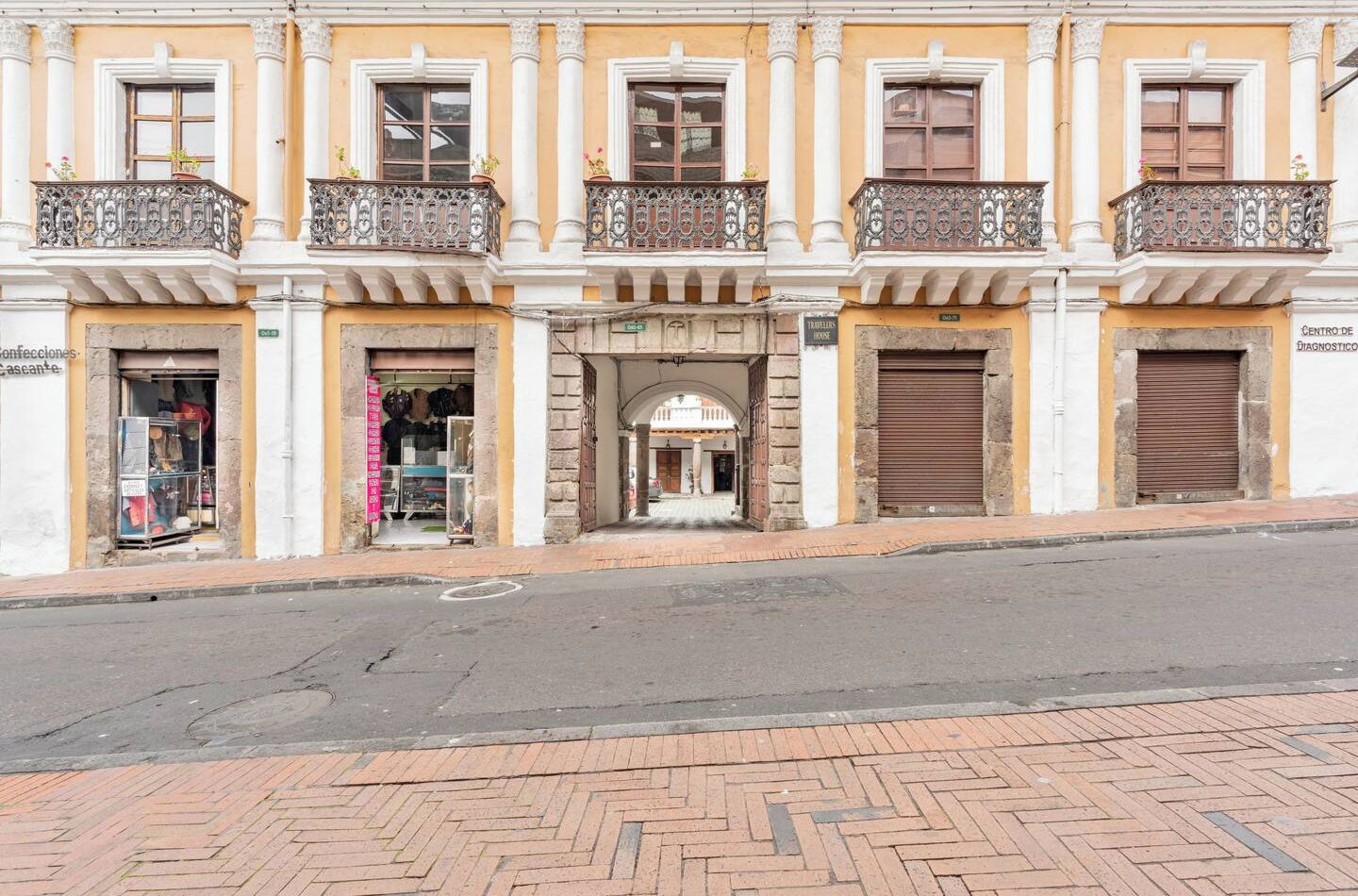 A building with a central entrance, two shops on either side, and a closed shutter on the right.