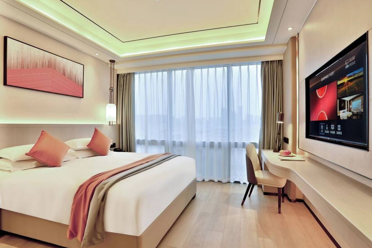 Een moderne hotelkamer met een groot bed, een bureau en een televisie aan de muur.