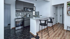 Una cocina moderna con una isla central, salpicadero a cuadros negros y grises, y suelo de madera.