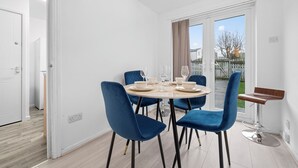 A dining area with a round table, blue chairs, and a bar stool.