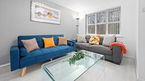 A modern living room with two sofas, a glass coffee table, and a large window.