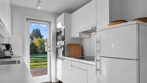 Een moderne keuken met witte kasten, een ingebouwde oven en een grote koelkast.