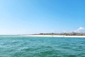 Une plage à l’eau turquoise et limpide, bordée d’un rivage sablonneux.