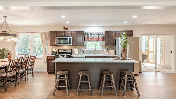 A spacious kitchen with a large island, wooden chairs, and a dining table. - The Hangout Haven - theater, pickleball, ping pong, hot tub, karaoke, games (Long Pond)
