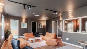A modern living room with a sofa set, a black leather chair, a coffee table, and a large mirror. - The Hangout Haven - theater, pickleball, ping pong, hot tub, karaoke, games (Long Pond)