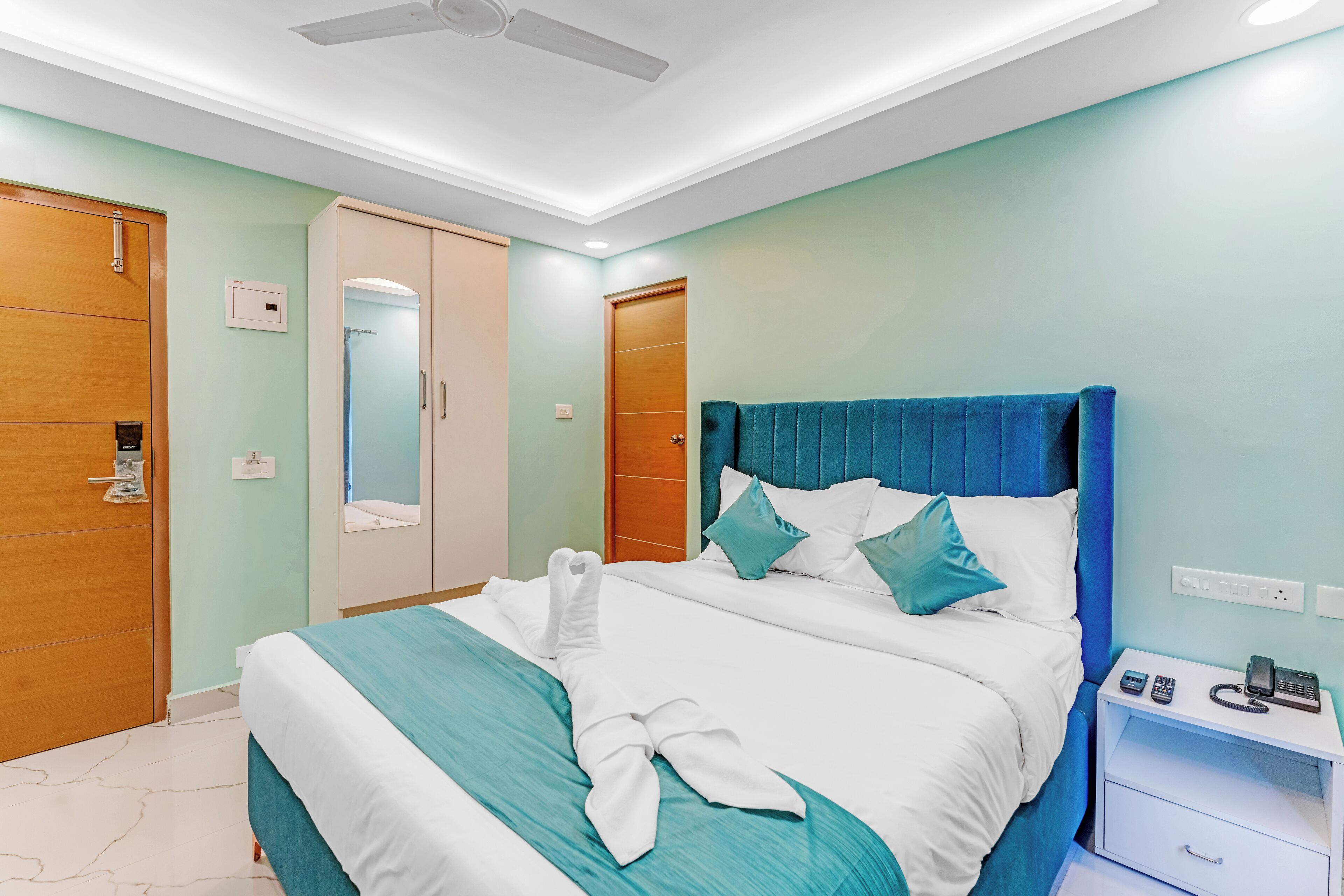 Una habitación de hotel con cama, mesita de noche y ventilador de techo.
