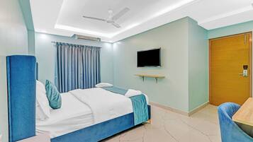 Una habitación de hotel con cama, escritorio, silla, televisor y puerta.