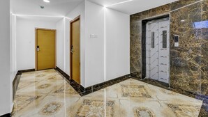 A hallway with a marble floor, a wooden door, and a wall with a marble pattern.