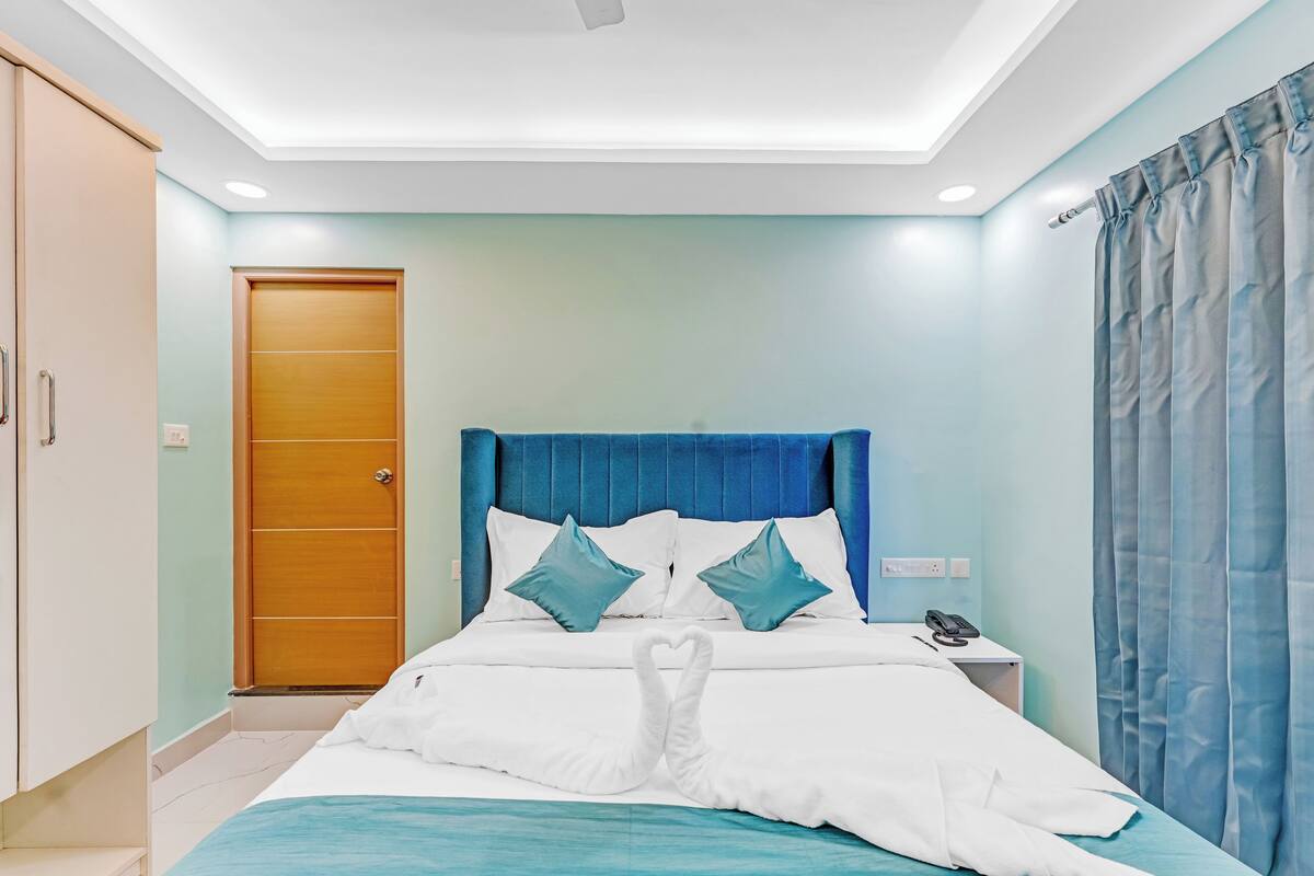 A hotel room with a bed, a nightstand, a wardrobe, and a door.