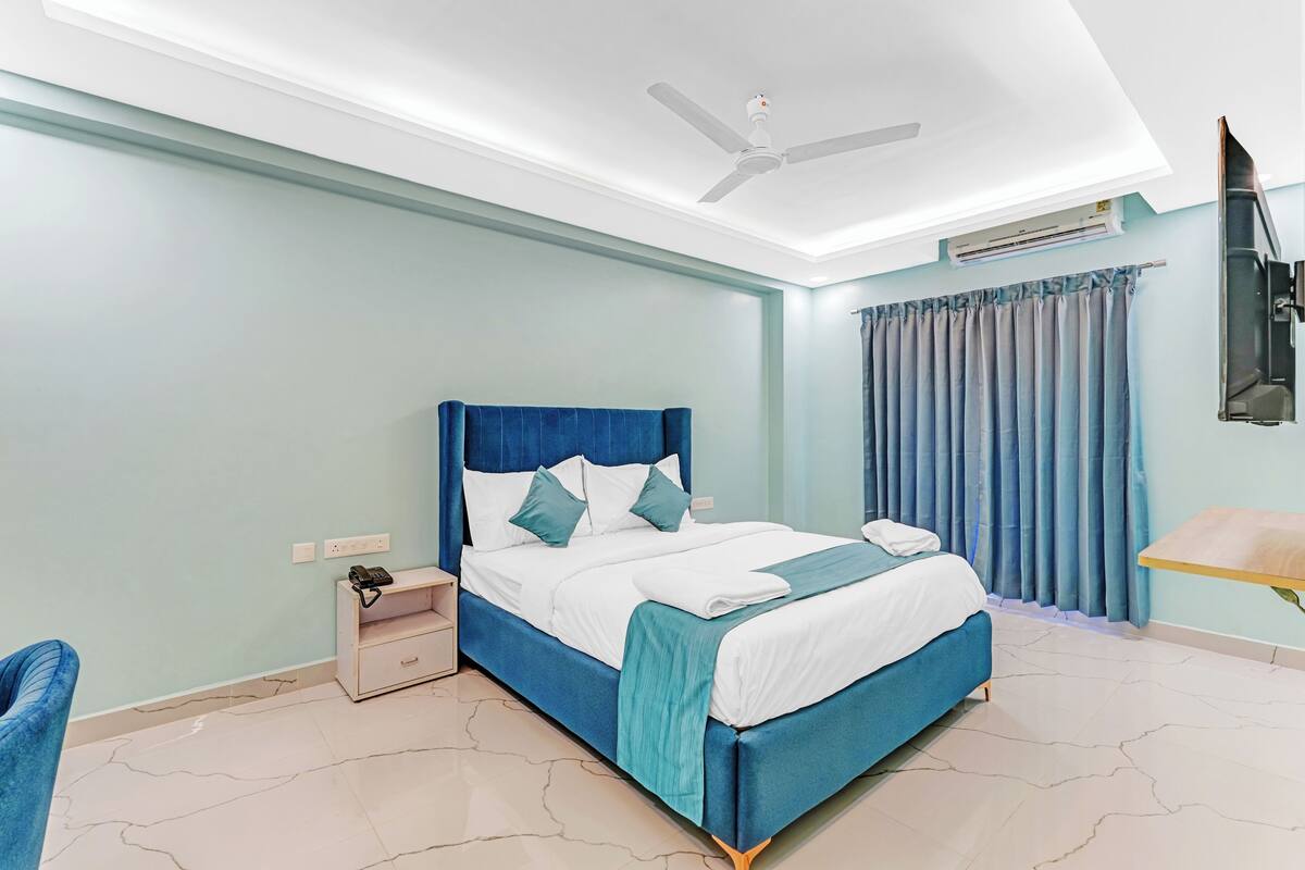 A modern bedroom with a bed, nightstand, and a ceiling fan.