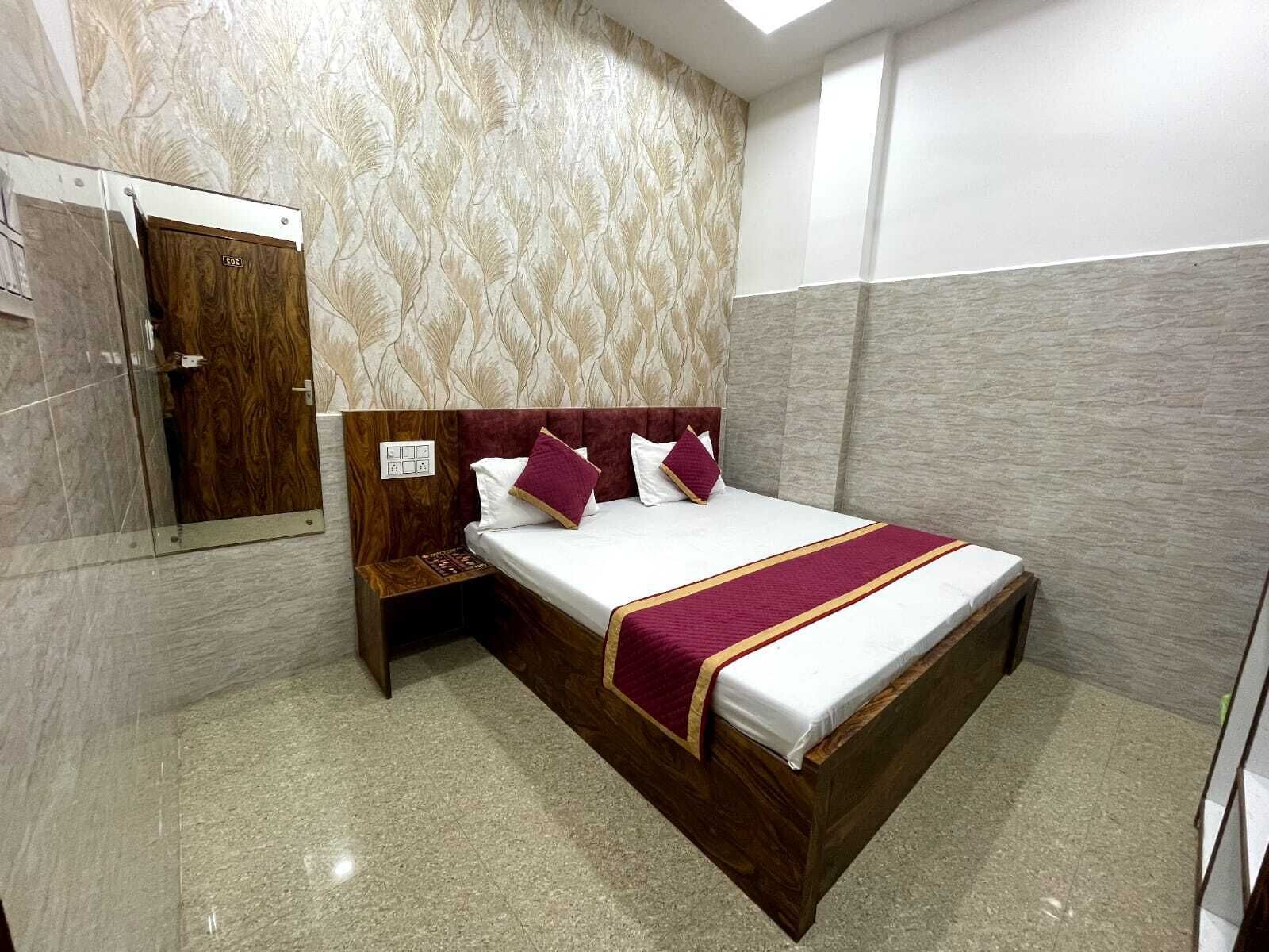 Una habitación de hotel con cama, mesita de noche de madera, espejo y pared con diseño.