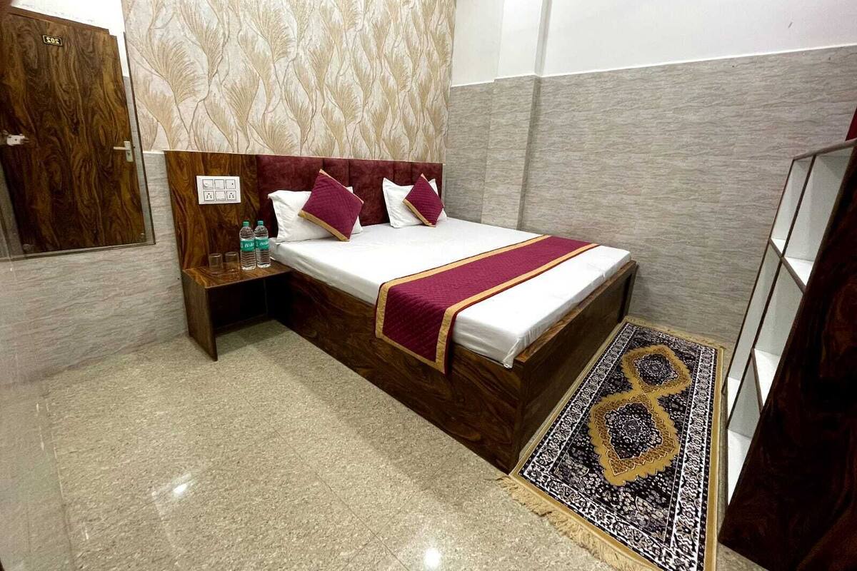 A hotel room with a bed, a nightstand, a mirror, and a patterned wall.