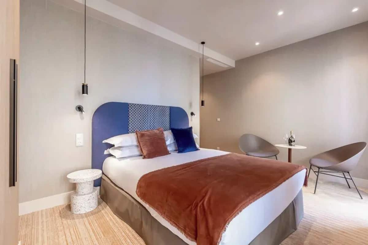 A modern hotel room with a large bed, a small round table, and a chair.