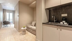 A modern kitchen with a marble countertop, a built-in sink, and a small round table with a plant. - Suites FL by Sweett (Paris)