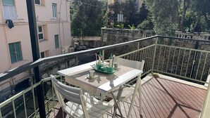 A balcony with a table and chairs, a railing, and a view of buildings and trees. - [200m from the Sea] 3 min from Porto Sole (Sanremo)