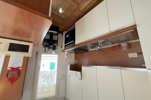 A kitchen with white cabinets, a stainless steel range hood, and a microwave.