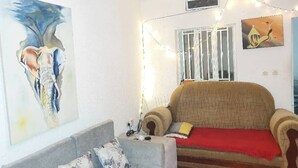 Una sala de estar acogedora con un sofá estampado, un plaid rojo y un cuadro en la pared.