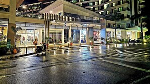 A modern hotel with a covered entrance, multiple floors, and a wet ground suggesting recent rain.