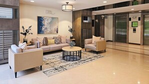 A modern lobby with a sofa, chairs, a coffee table, and an elevator.
