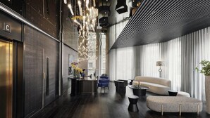 Eine moderne Hotelhalle mit dunklem Holzboden, einer Rezeption, einer Couch und einem Couchtisch.