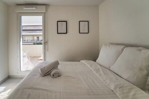 Una camera d'albergo con un letto, una porta che dà su un balcone e due opere d'arte appese al muro.