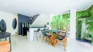 A modern kitchen with a central island, bar stools, and a dining area with a glass table and chairs. - STEP OUT OF THE ORDINARY SoHo meets- Berawa -Canggu BALI (Bali)