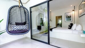 A modern room with a hanging chair, a white sofa, and a glass door leading to a bathroom. - STEP OUT OF THE ORDINARY SoHo meets- Berawa -Canggu BALI (Bali)