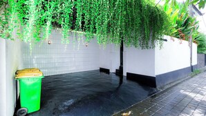 A clean, tiled indoor space with hanging green plants and a green trash bin. - STEP OUT OF THE ORDINARY SoHo meets- Berawa -Canggu BALI (Bali)