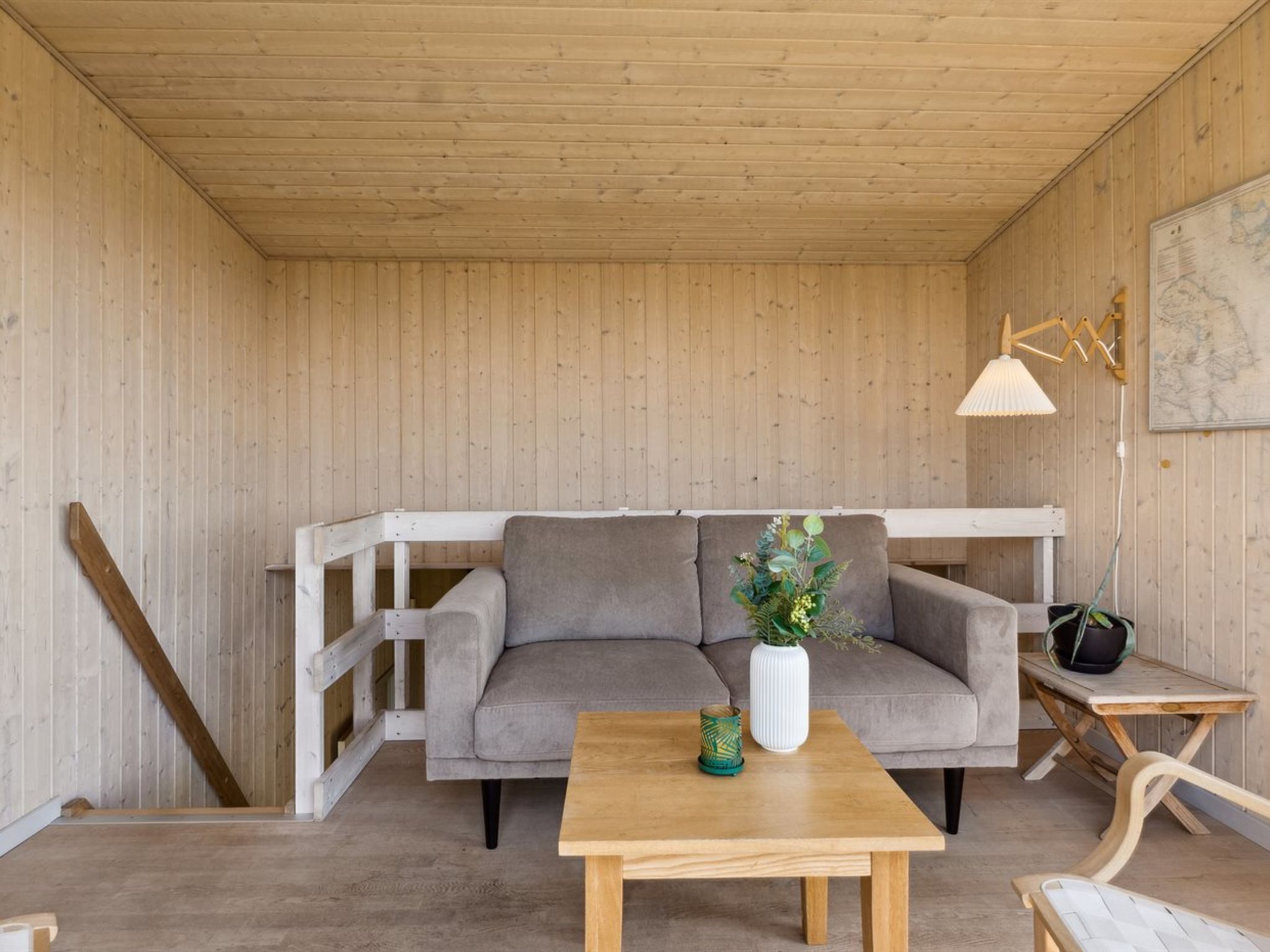 A cozy room with a grey sofa, a wooden table, and a small side table with a lamp.